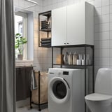 Modern laundry room with white ENHET units: shelves with black accents, a cabinet, and a rolling laundry bag.