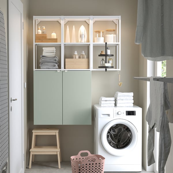Mint green ENHET shelves with towels, supplies, iron. Washer, basket, stool underneath. Clothes hang right.