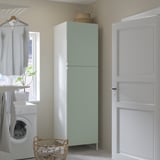 Modern laundry closet with large green cabinet, white washer, wicker basket, and hanging shirt.