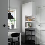 Modern living room with white ENHET shelves, black furniture, potted plant, and minimalist design.