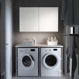 Modern laundry setup with ENHET white appliances - washer, dryer, countertop, and cabinets.
