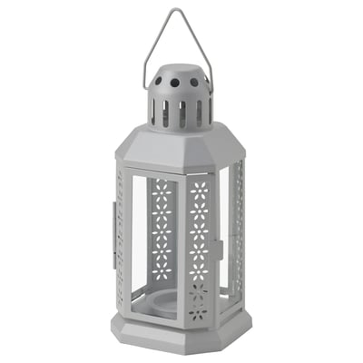 Light gray ENRUM lantern, hexagonal shape, made of steel and glass, with floral cutouts and handle on top.