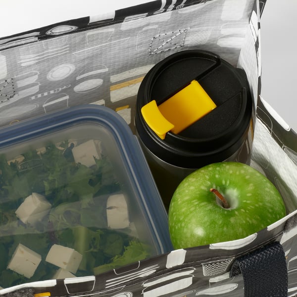 Open insulated travel mug beside green apple and salad container in lunch bag.