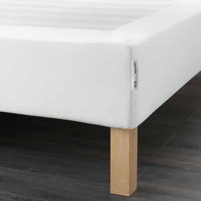 White bed with wooden legs. Mattress base makes bed higher, supports mattress.
