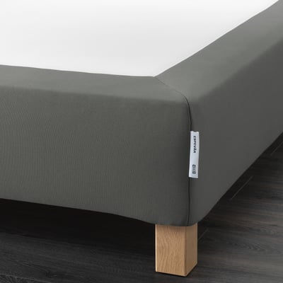 A grey upholstered bed frame with wooden legs, providing a higher bed height and mattress support.