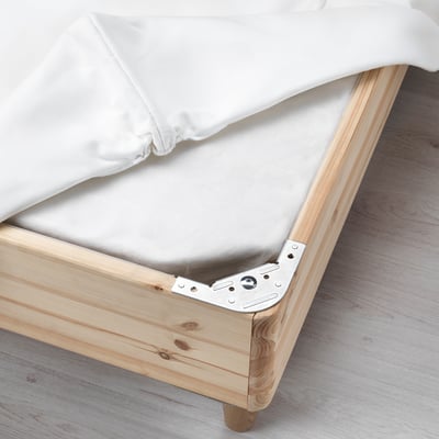 Wooden bed frame with metal corner bracket and white mattress.