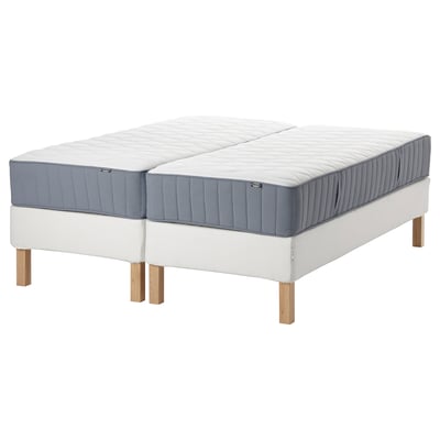 Two blue and white mattresses on white frames with wooden legs.