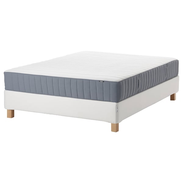 Displays a white espevär mattress on a valevåg white bed base. The mattress has blue and white vertical stripes, and the bed base has wooden legs.