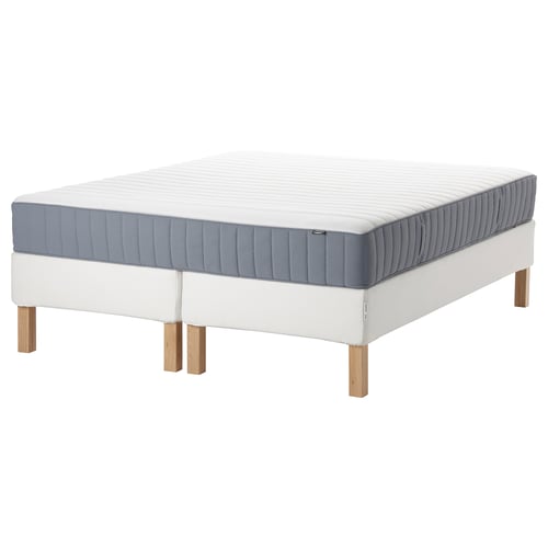 Modern white bed with grey mattress, wooden legs, upholstered base.