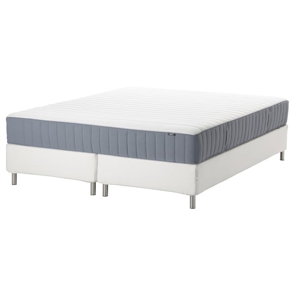 White bed with blue-trim mattress on sturdy frame.
