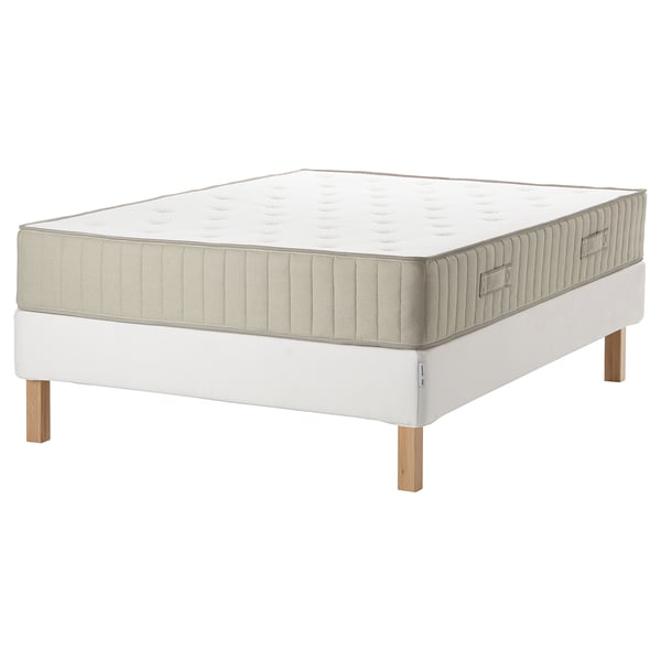 A white ESPEVÄR/VATNESTRÖM bed with a plush mattress, wooden legs, and a beige trim. Its a rectangular bed with a quilted design.