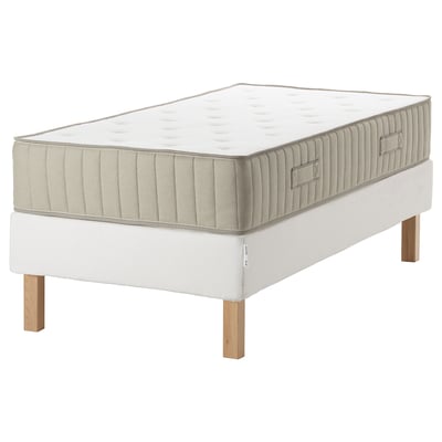 A modern white bed with an espevar base and vatnestrom mattress, featuring wooden legs and a quilted design.