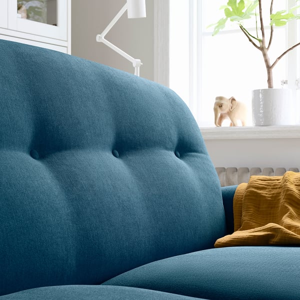 Blue curved sofa with mustard cushion, modern design, large windows, elephant decor.