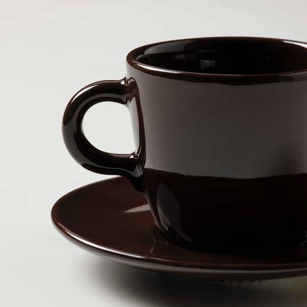 Dark brown cup and saucer set with glossy finish on a plain surface.