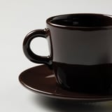 Dark brown cup and saucer set with glossy finish on a plain surface.