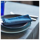 A dark blue FÄRGKLAR plate with a folded napkin and cutlery.