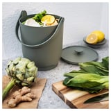 Dark green kitchen caddy holds fruit, veg scraps. Bags not needed, easy to clean.