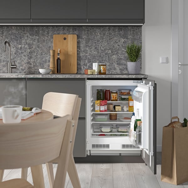 Modern kitchen with FASTNÄS fridge, shelves, and food.