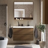 Modern bathroom with wooden vanity, mirror cabinet, and built-in lighting. Tall, sleek design fits between tiles, with plant and towels adding color.