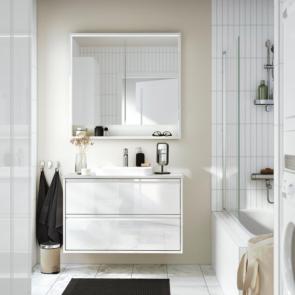Modern bathroom with FAXÄLVEN mirror cabinet w/light, sink, shower, minimalist design.