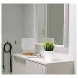 Small white FEJKA plant in a modern setting, next to glasses on a cabinet top.