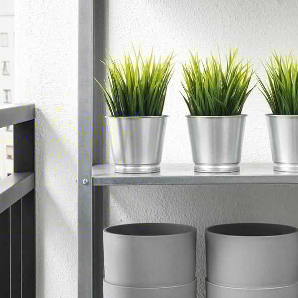 Three silver pots with green artificial plants on a shelf. Ideal for indoor/outdoor use, low maintenance.