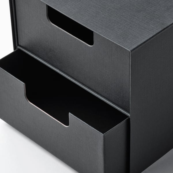 Black mini storage unit with textured paperboard drawers; smooth handles, alternating open and closed positions, neat and modern design.