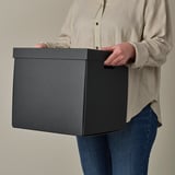 Person holding storage box with handles. Ideal for kallax shelves, sturdy for daily use.