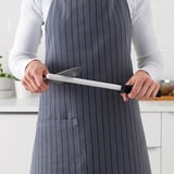 Person holding a knife sharpener in a kitchen.