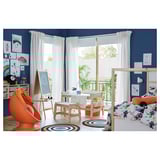 Bright childrens room with blue walls, large window, wood furniture, orange chair, white table with drawers, colorful rugs, and wall art.