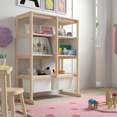 Wooden FLISAT storage unit with shelves and trofast boxes, filled with kids books, toys, and frames.