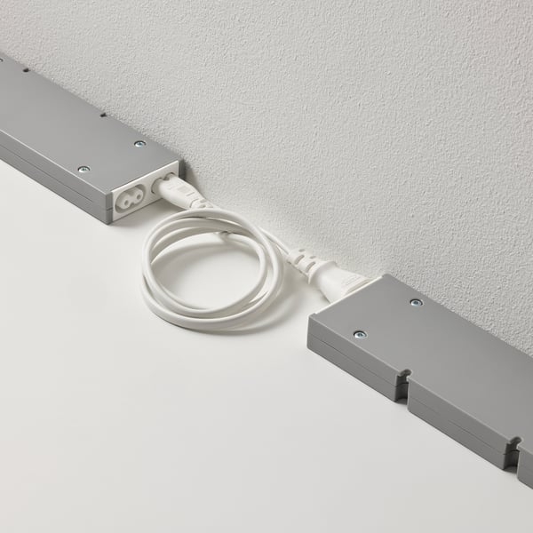 Two grey rectangular FÖRNIMMA devices connected by a white cord, used to link and control multiple lamps with one mains supply.