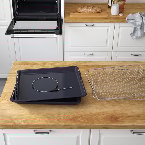 Kitchen counter with oven accessories: baking tray, cooling rack, and integrated meat probe, indicating versatile baking and cooking functions.