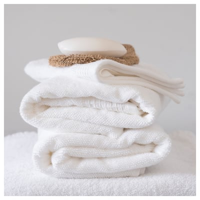 Stack of folded white towels with bath accessories. Clean, fresh look.