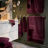 Modern bathroom with dark green walls, white cabinet, and burgundy towels.