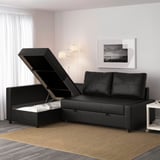 Black convertible sofa with storage, partially opened. Modern living room with grey walls, large window, and artwork above.
