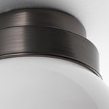 Rustic ceiling lamp with ribbed metal top and frosted glass shade, emitting warm light.
