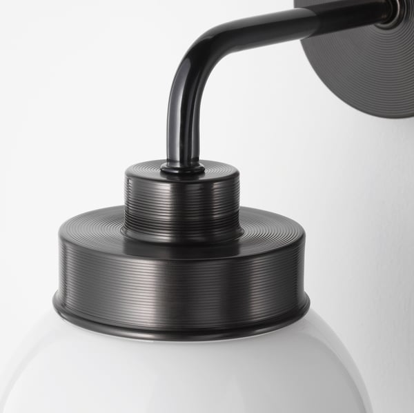 Modern wall lamp with frosted glass shade and black metal arm.