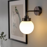 Wall-mounted lamp with round glass shade, warm light, ideal for bathroom.