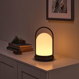 Modern lantern on a sideboard, casting warm, inviting light. Accompanied by books and pine cones, it adds a cozy ambiance.
