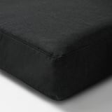 Black outdoor cushion cover, smooth texture, corner detail visible, heavy-duty stitching, water-resistant.