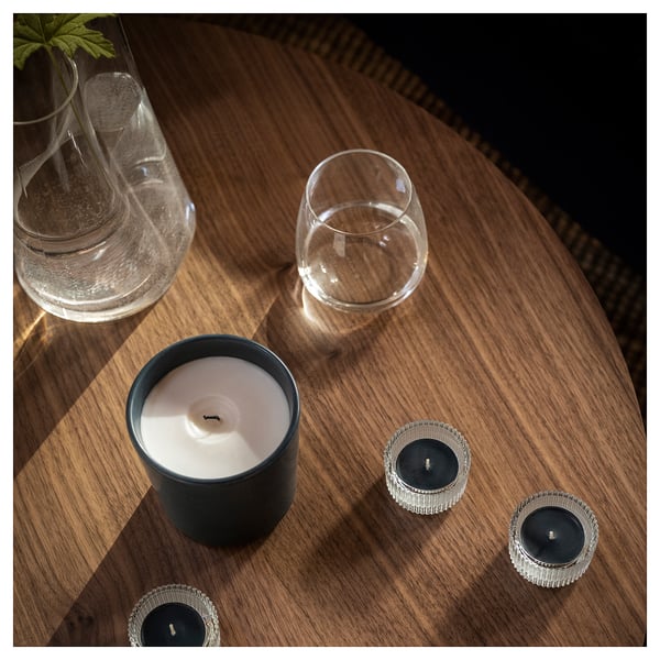 Image a wooden table with two glass goblets and three candles: one large black candle and two smaller silver ones.