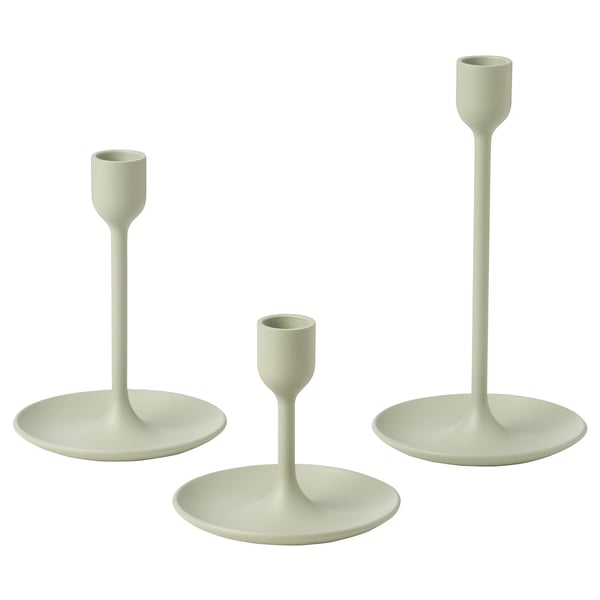 Three light green candlesticks in varying heights, simple modern design, made of aluminum with felt pads, arranged in a triangle.