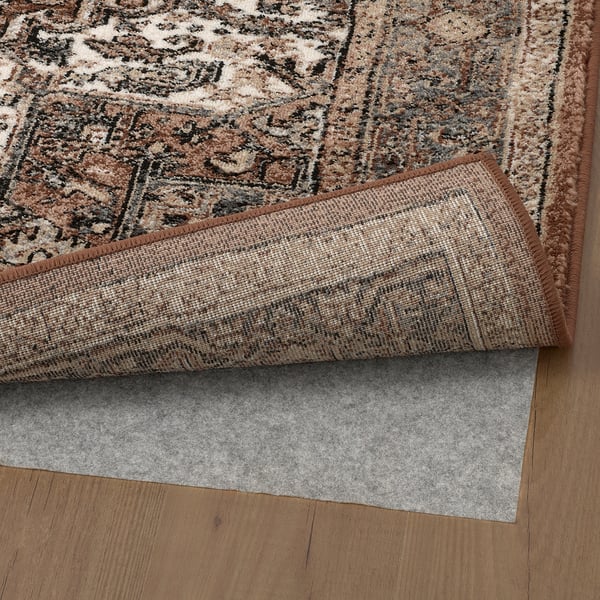 Rug with grip pad underneath, displayed on wooden floor.