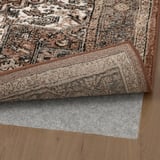 Rug with grip pad underneath, displayed on wooden floor.