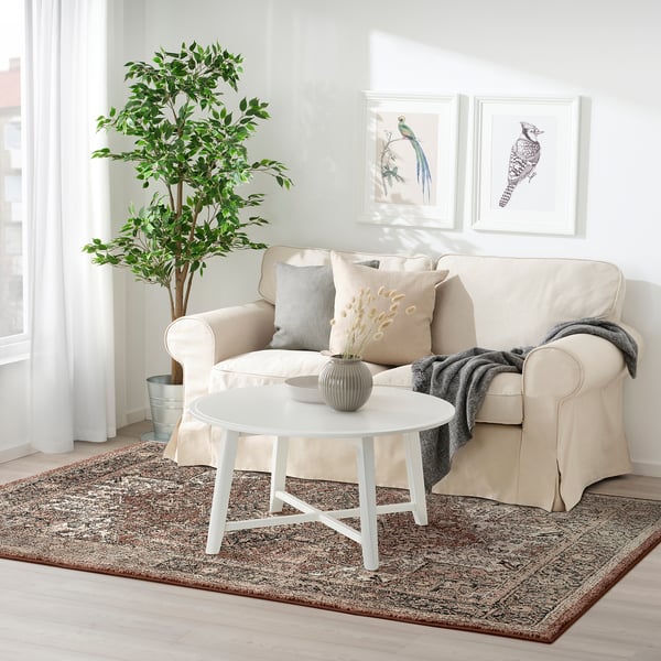 Cozy living room with beige rug, matching couch, gray cushions, and white coffee table, blending oriental and modern styles for warmth.