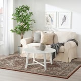 Cozy living room with beige rug, matching couch, gray cushions, and white coffee table, blending oriental and modern styles for warmth.