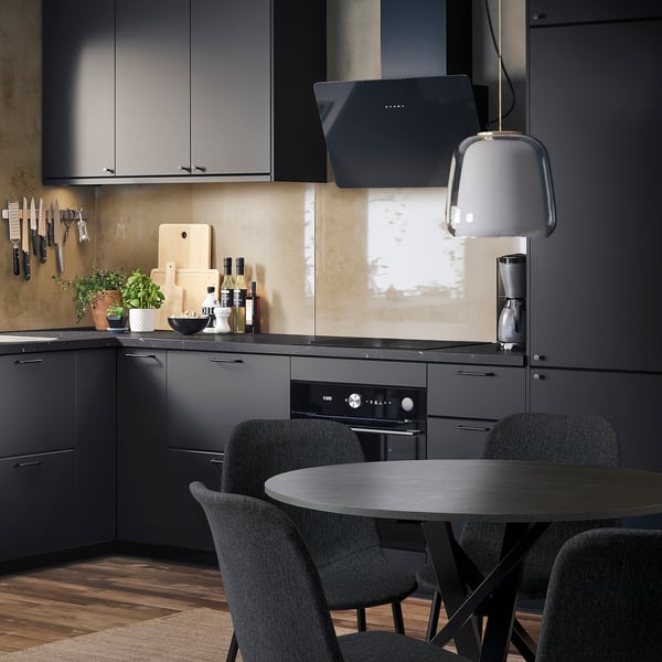 Modern kitchen with gray GALLERUD chairs around dark table. Black cabinets, wood floor. Recycled, durable chairs.