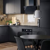 Modern kitchen with gray GALLERUD chairs around dark table. Black cabinets, wood floor. Recycled, durable chairs.