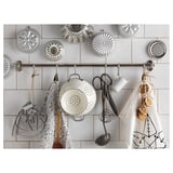 Kitchen rack with white enamel colander, utensils, and patterned aprons.